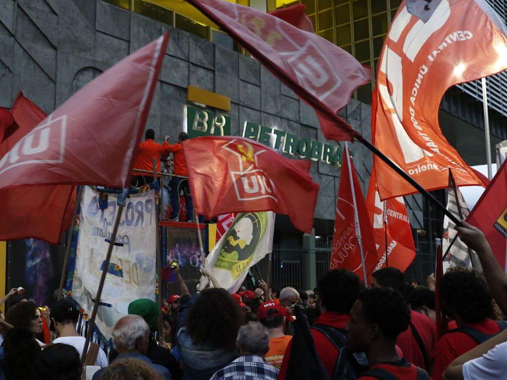 Trabalhadores segurando bandeiras em ato pelos 70 anos da Petrobras, que ocorreu em frente ao edifício sede da empresa.