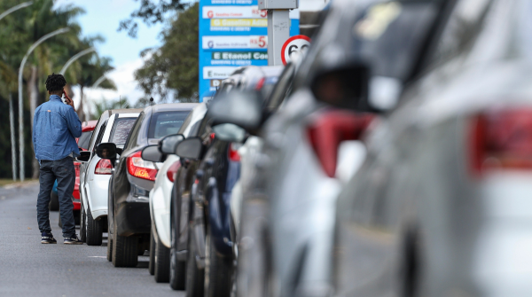 Imagem de uma fila de carros em um posto de combustível; ao fundo, uma tabela de preços. Foto: Marcelo Camargo/Agência Brasil.